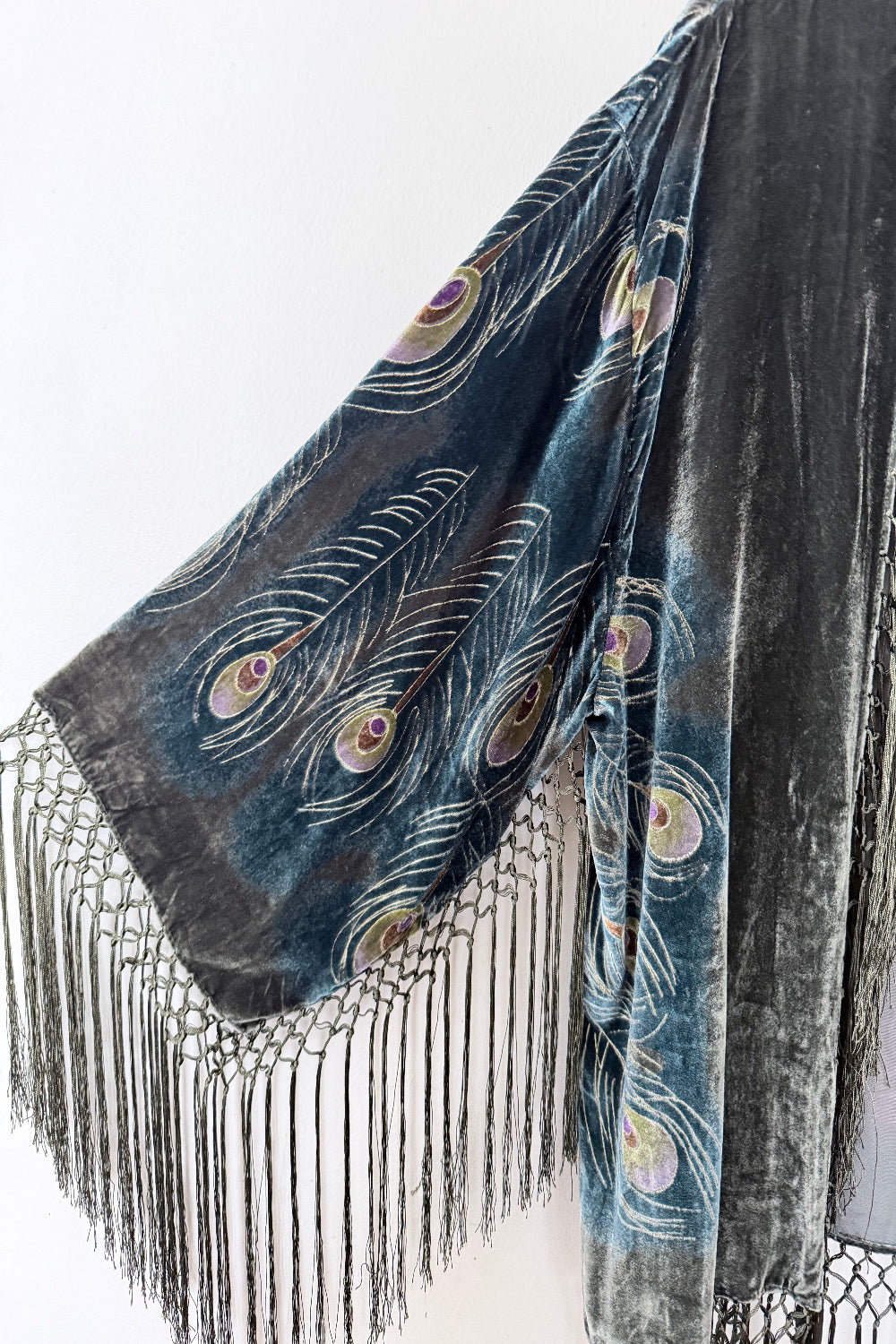 Velvet silk jacket peacock feather design and fringes on a white background