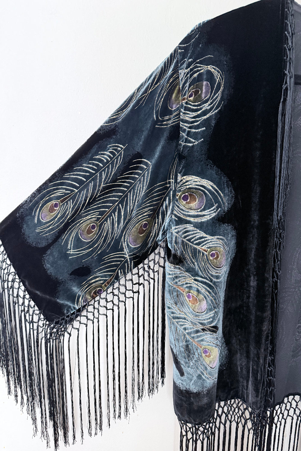 Black velvet silk jacket with peacock feather pattern and fringes on a white background