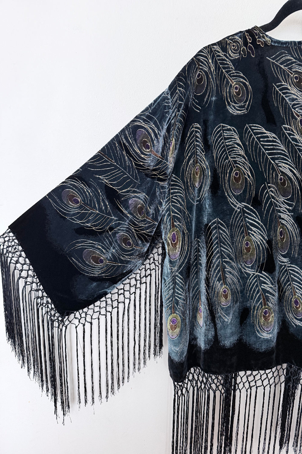 Black velvet silk jacket with peacock feather pattern and fringes on a white background
