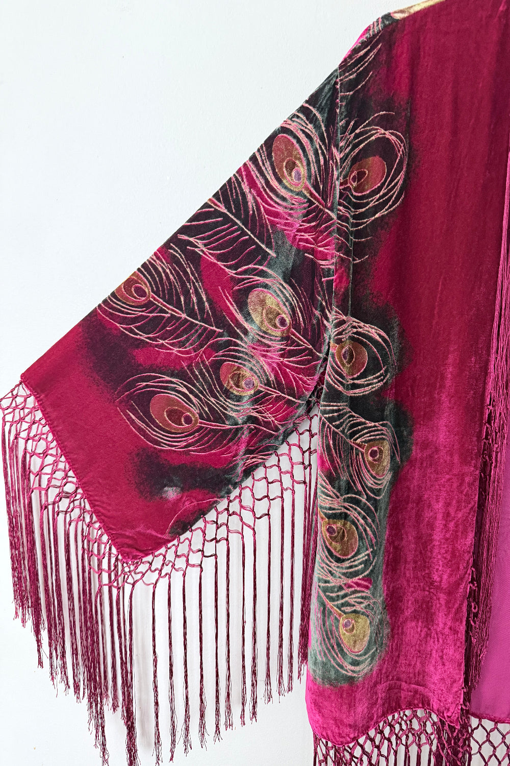 Red velvet silk jacket with peacock feather pattern and fringes on a white background