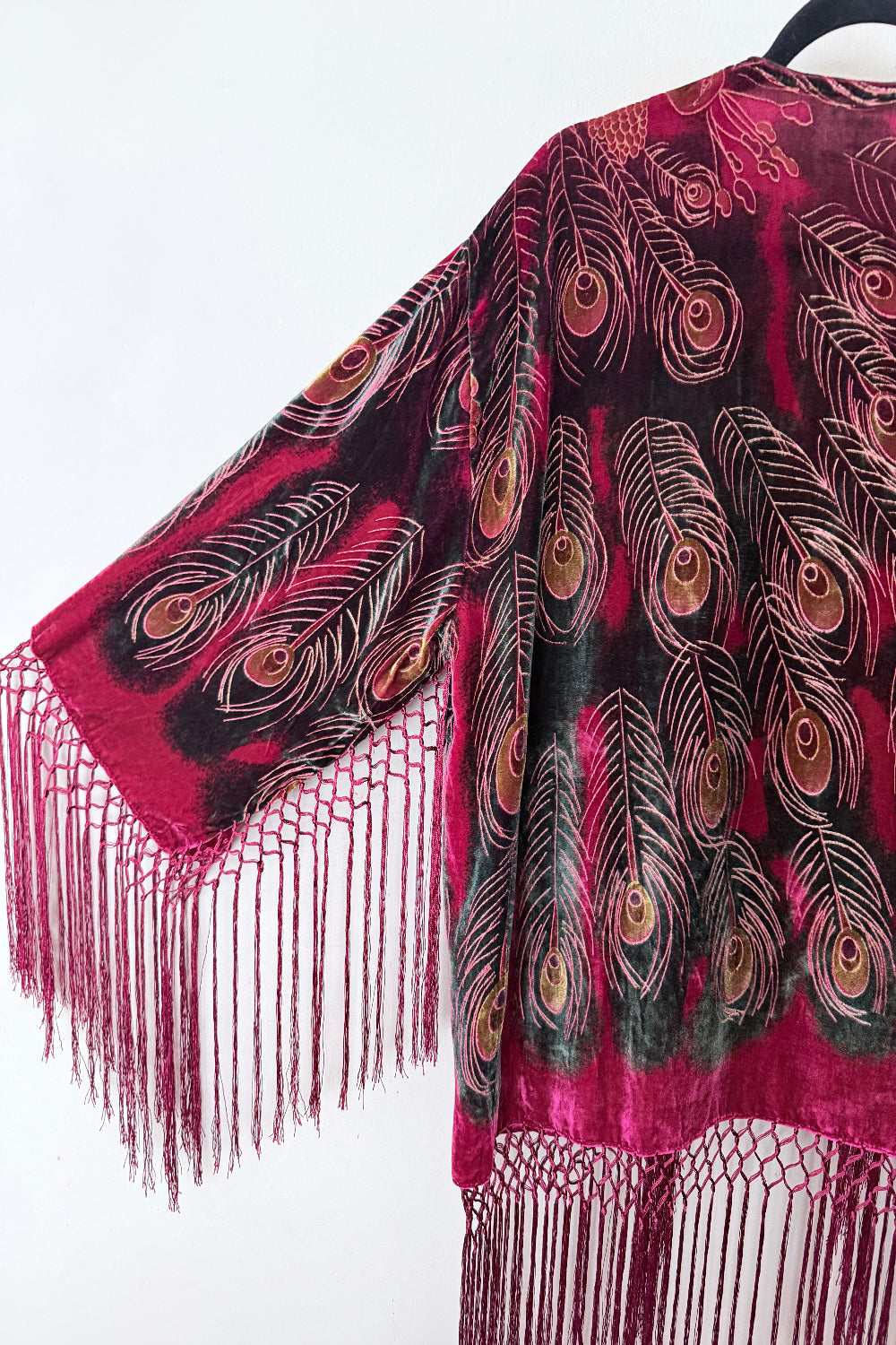 Red velvet silk jacket with peacock feather pattern and fringes on a white background