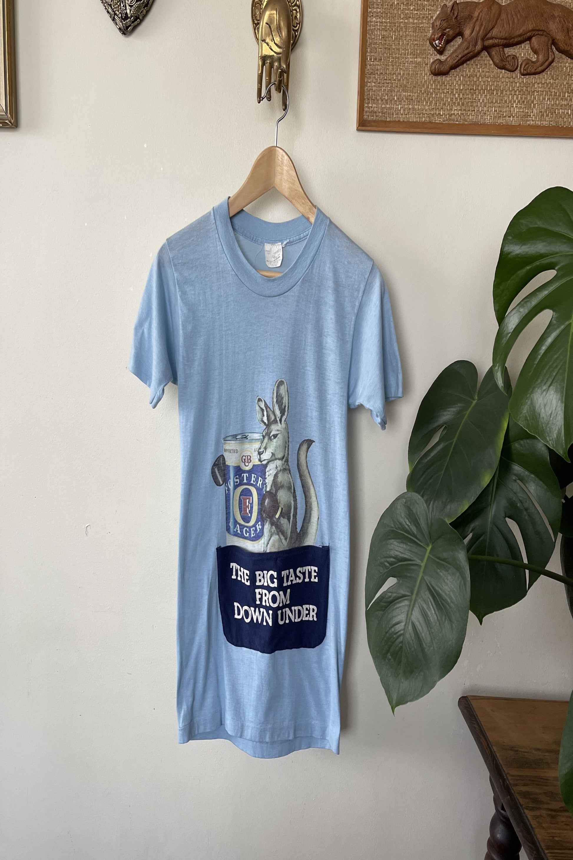 A vintage blue T-shirt with a graphic of a kangaroo and the text 'THE BIG TASTE FROM DOWN UNDER', along with 'BOXING KANGAROO' and the Foster's Lager logo.